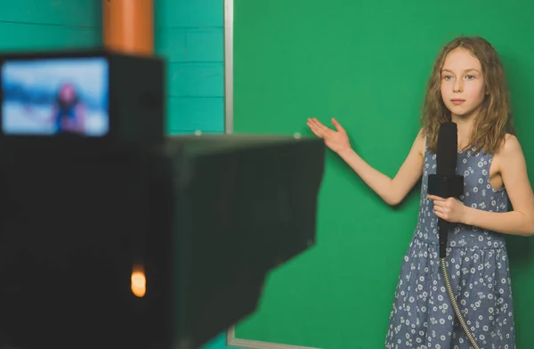 小女孩与话筒站立在照相机前面在绿色屏幕上. — 图库照片