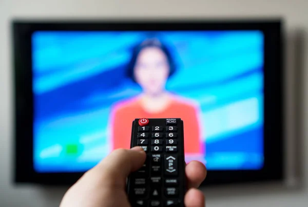 Male hand holding TV remote control. News block. — Stock Photo, Image