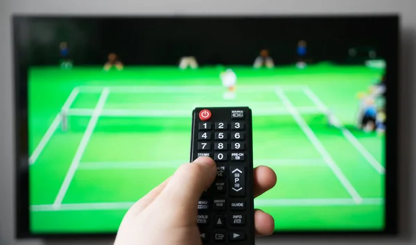 Mão masculina segurando TV controle remoto. Torneio de tênis . — Fotografia de Stock