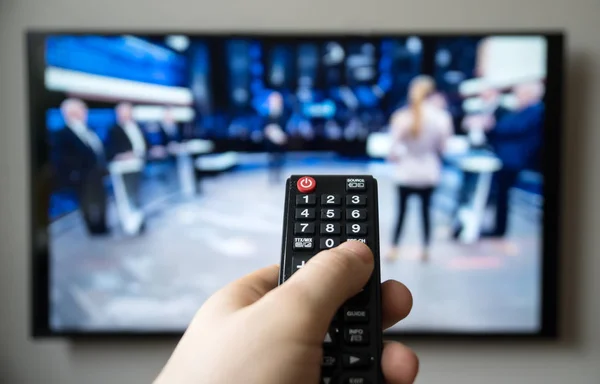 Mão masculina segurando TV controle remoto. talk show . — Fotografia de Stock