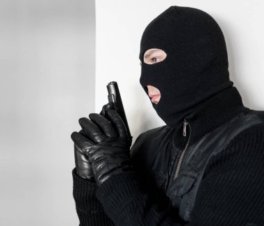 Silahlı adam bir duvarın arkasına saklanarak yün.