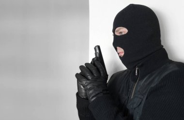 Silahlı adam bir duvarın arkasına saklanarak yün.