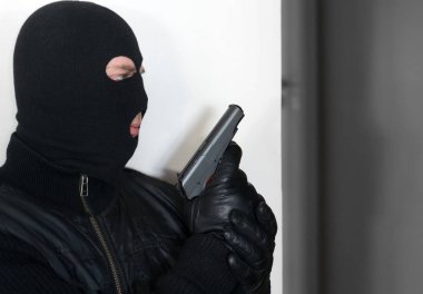 Silahlı adam bir duvarın arkasına saklanarak yün.