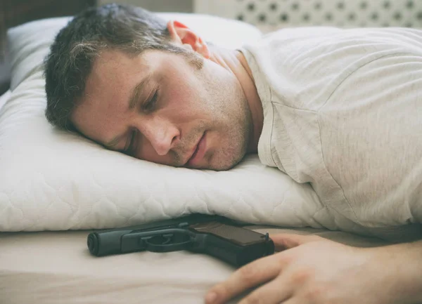 Homem dormindo na cama com arma perto de sua mão . — Fotografia de Stock