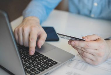 İnternet dükkanında ödemek için kredi kartı kullanan adam.