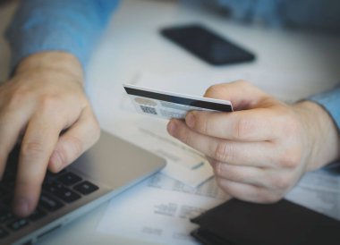 İnternet dükkanında ödemek için kredi kartı kullanan adam.