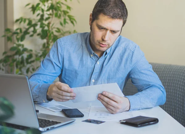 Człowiek ogląda jego miesięczne rachunki w domu. — Zdjęcie stockowe