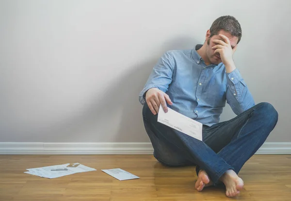 Very upset man sitting at the floor with bills. — Stock Photo, Image