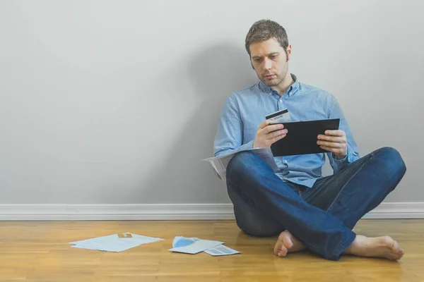 Przystojny mężczyzna przy użyciu komputera typu tablet i karty kredytowej a rachunki trzeba płacić. — Zdjęcie stockowe