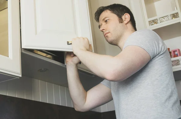 Tuttofare professionale che installa la porta dell'armadio in cucina. — Foto Stock