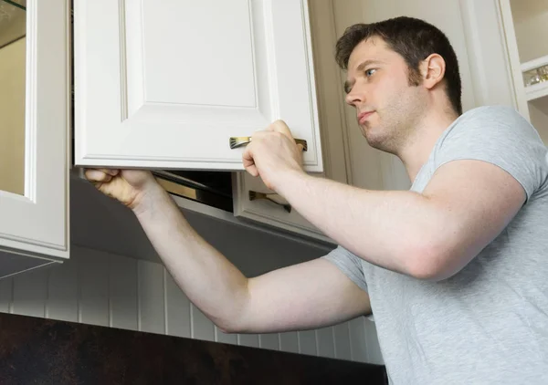 Professionele klusjesman installeert kastdeur in de keuken. — Stockfoto