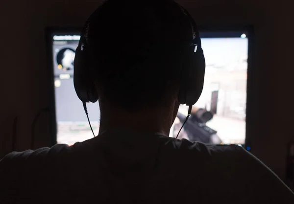 Hombre en auriculares jugando juego de disparos de ordenador en la noche . — Foto de Stock