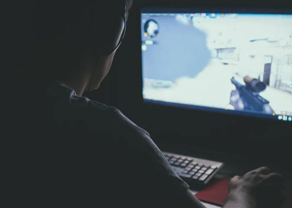 Homem em fones de ouvido jogando jogo de tiro de computador à noite . — Fotografia de Stock