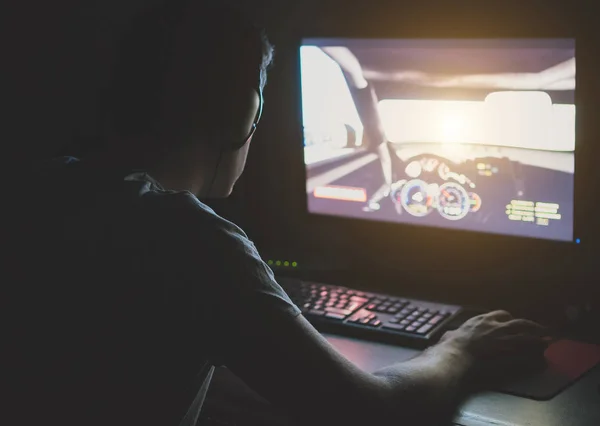 Muž v sluchátka hrají počítačová auto závodní hra v noci. — Stock fotografie