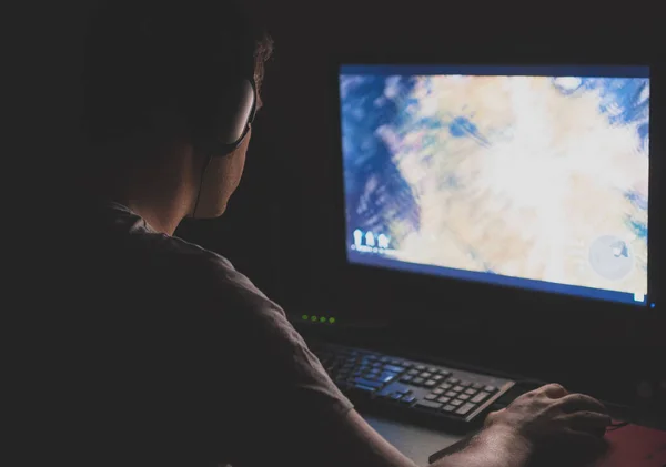 Muž v sluchátka hrají počítačové hry strategie v noci. — Stock fotografie