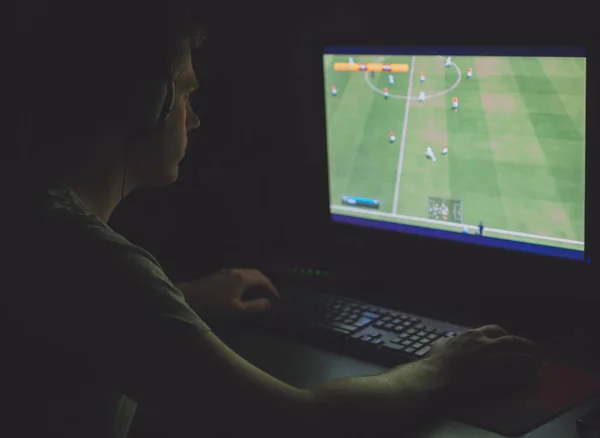Ο άνθρωπος σε ακουστικά παίζοντας ποδόσφαιρο παιχνίδι στον υπολογιστή τη νύχτα. — Φωτογραφία Αρχείου