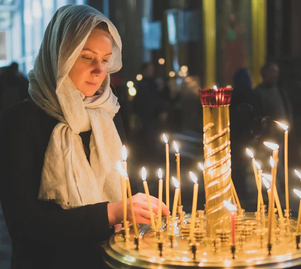 Frau zündet Kerze in russisch-orthodoxer Kirche an. — Stockfoto