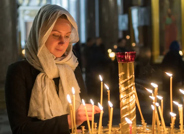 Frau zündet Kerze in russisch-orthodoxer Kirche an. — Stockfoto