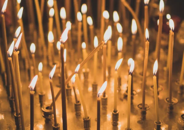 Many candles glowing on table in the church. — Stock Photo, Image