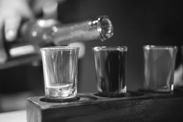 Schnapsgläser mit Schnaps in der Bar. schwarz-weiß. — Stockfoto