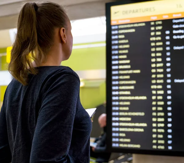Kvinna framför flyginformations kortet, kontrollera sin flygning. — Stockfoto