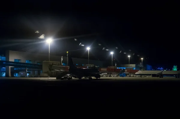 Passenger planes near hangar at night airport.