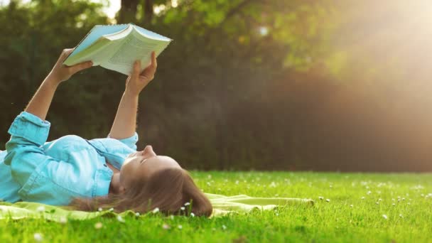女は草の上に横になり本を読む — ストック動画