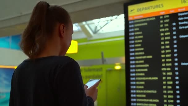 Frau Vor Der Fluginformationstafel Ihren Flug Überprüfen — Stockvideo