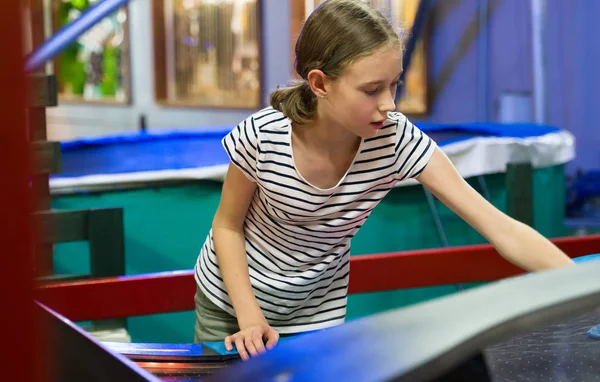 Klein meisje speelt air hockey in pretpark. — Stockfoto