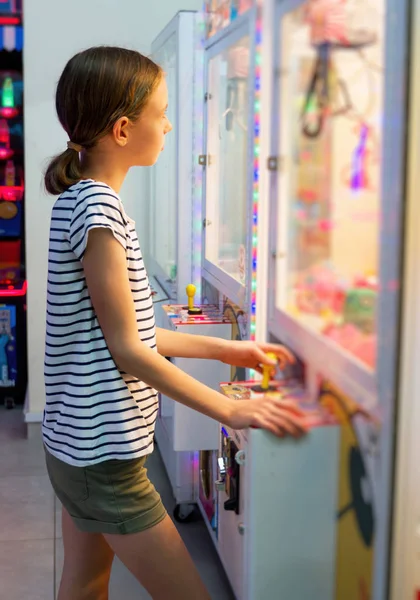 Little girl playing claw crane in theme park. — Stock Photo, Image