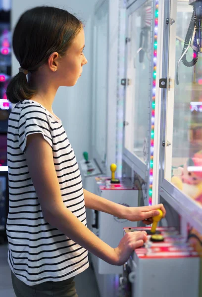 Little girl playing claw crane in theme park. — Stock Photo, Image