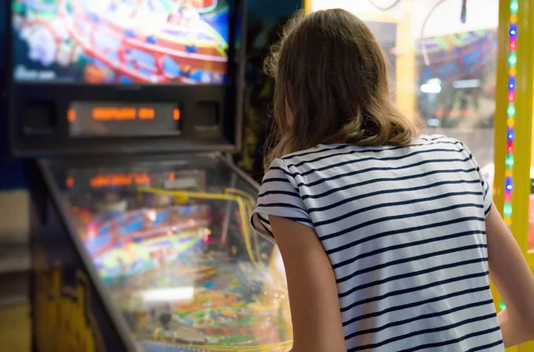 Klein meisje spelen flipperkast spel in themapark. — Stockfoto