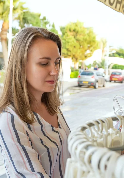 Mooie vrouw kiezen jurk in straat winkel. — Stockfoto