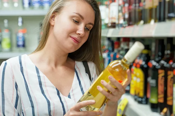 Krásná žena vybírá bílé víno v supermarketu. — Stock fotografie