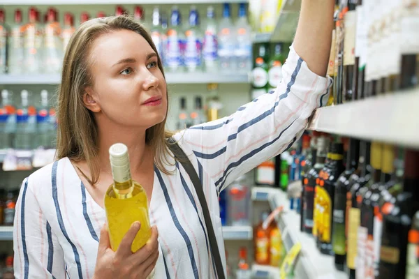 Mulher bonita escolhendo vinho branco no supermercado . — Fotografia de Stock