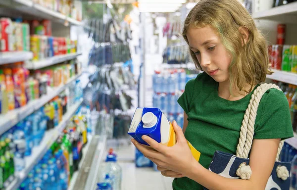 Menina escolhendo suco de laranja no supermercado . — Fotografia de Stock