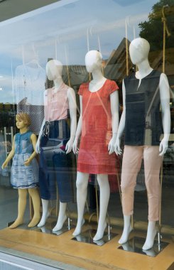 Mankenler yazlık kıyafetleri camın arkasında reklamını yaparlar..