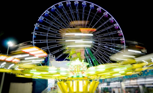 Paseo en huracán y noria en el parque de atracciones de la ciudad por la noche . — Foto de Stock