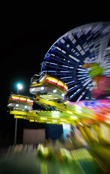 Hurricane ride and ferris wheel in the city amusement park at evening. Stock Image