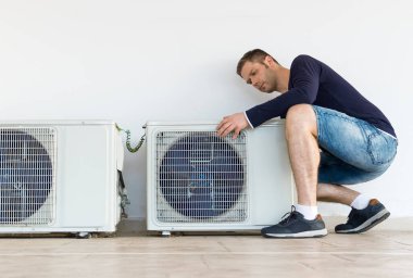 Male technician installing air-conditioning system. clipart