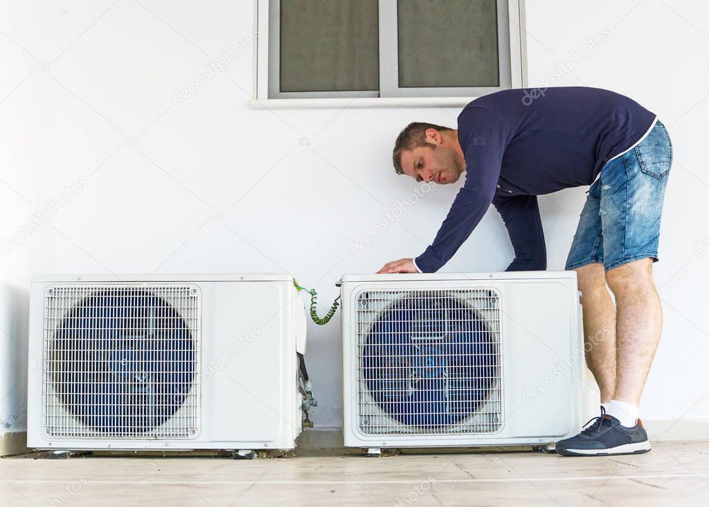 Male technician installing air-conditioning system.