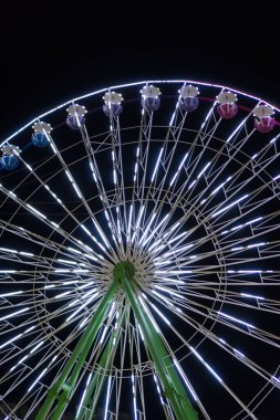 Gece şehir parkında renkli dönme dolap.