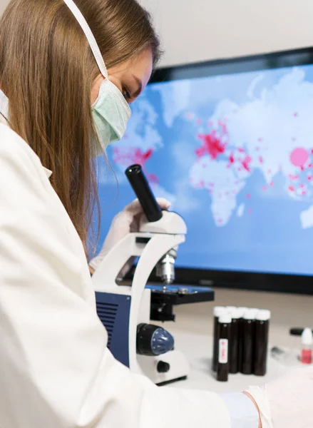 Scientist in medical mask in laboratory. On the background map with infections.