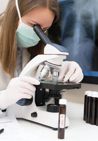 Scientist in medical mask in laboratory. Pneumonia x-ray film on background.