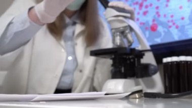 Laboratuvardaki bilim adamı Covid-19 örnek tüpü yerleştiriyor..