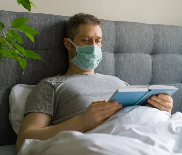 Sick Man Medical Mask Reading Book Bed Home Quarantine Concept — Stock Photo, Image