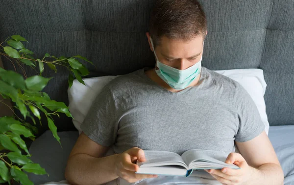 Sick Man Medical Mask Reading Book Bed Home Quarantine Concept — Stock Photo, Image