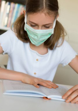 Karantina sırasında ders kitabı okuyan küçük bir kız. Coronavirus konsepti.