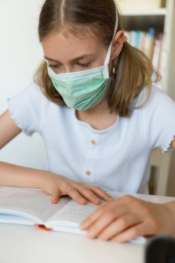Karantina sırasında ders kitabı okuyan küçük bir kız. Coronavirus konsepti.