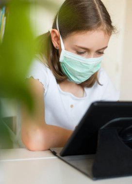 Karantina sırasında tablet kullanan küçük bir kız. Coronavirus konsepti.